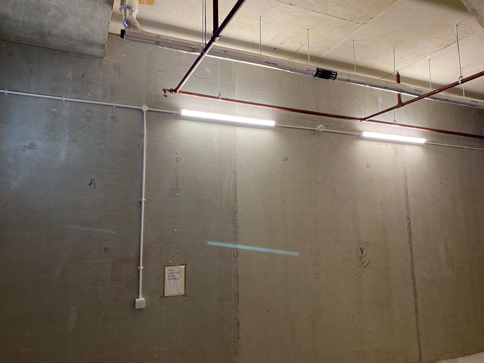 Commercial fit-out lighting with surface-mounted conduit and fluorescent tubes