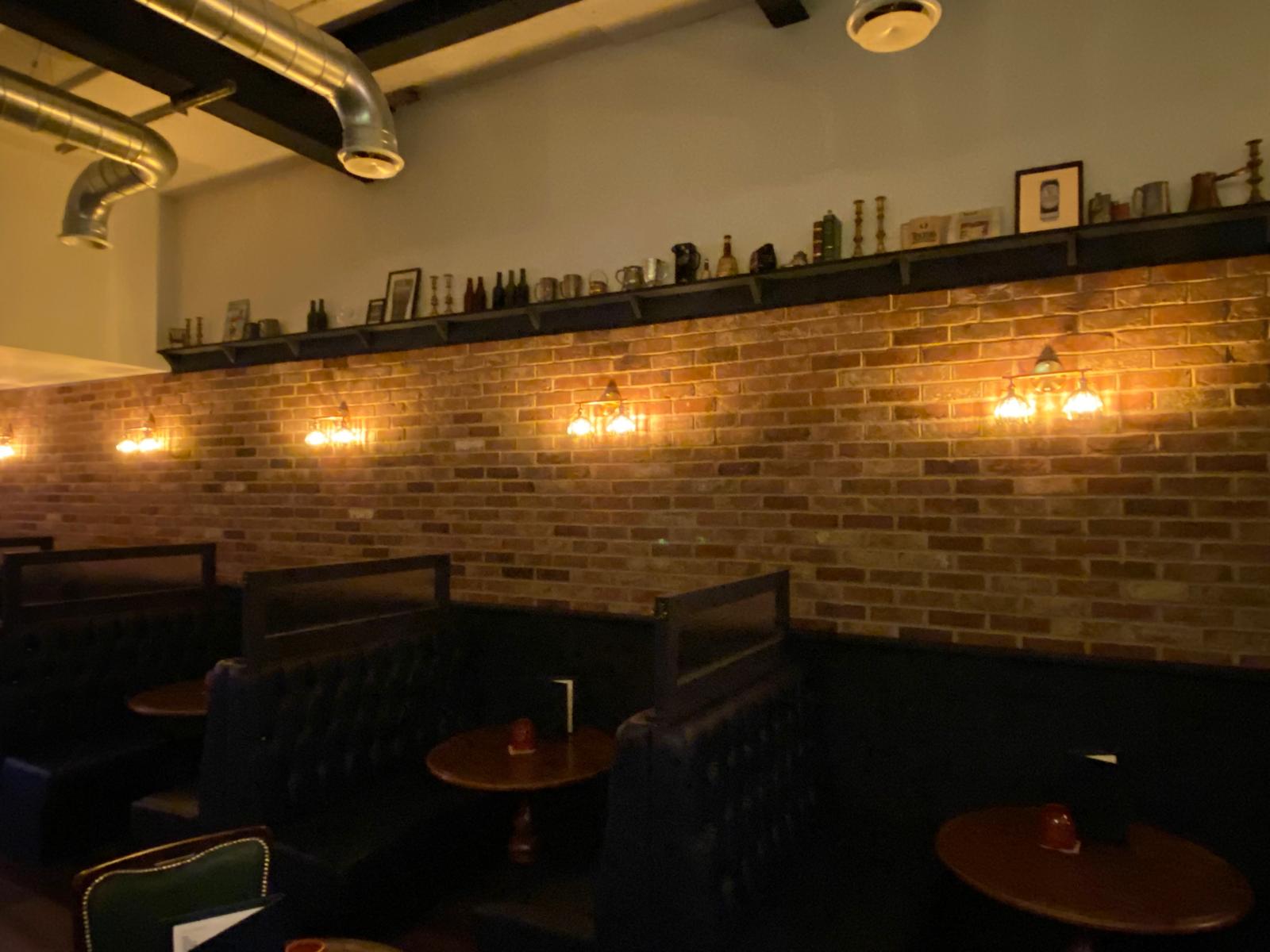 Pub booth seating with warm brick-wall sconce lighting, Fox Electrical commercial project, Liverpool